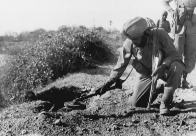An Indian soldier searching for mines with a metal detector by English Photographer